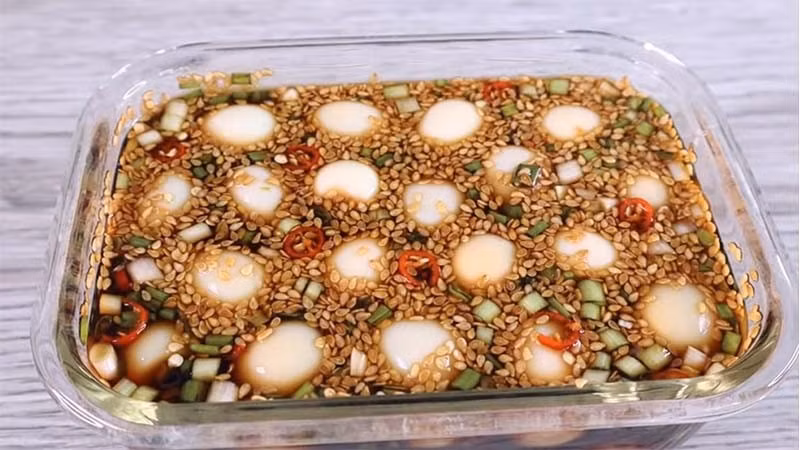 Từng “gây sốt” trên mạng xã hội, trứng lòng đào ngâm nước tương chinh phục người thưởng thức bởi vị béo mềm của trứng hòa quyện cùng nước tương đậm đà. Trứng gà được luộc vừa chín tới, bóc vỏ rồi ngâm trong hỗn hợp nước tương pha loãng với đường, chút muối và hành tây, hành lá thái nhỏ. Sau vài giờ để lạnh, trứng thấm đều gia vị, dùng kèm cơm trắng hay cháo đều rất hợp. Ảnh minh họa