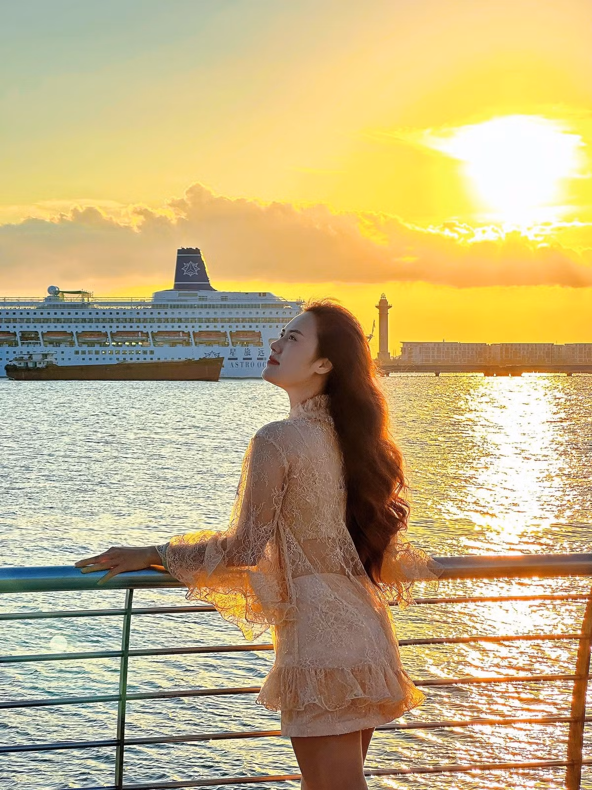 Khung cảnh hoàng hôn với tàu lớn cập bến, ánh sáng cuối ngày chiếu trên mặt biển, những dãy nhà cao tầng phía xa và nhịp sống sôi động của cảng tạo nên hiệu ứng điện ảnh tự nhiên, giúp bức ảnh trở nên sống động và cuốn hút. Ảnh Review Quảng Ninh