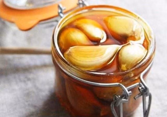 Bạn có thể thái mỏng vài tép tỏi, trộn cùng mật ong nguyên chất và để qua đêm trong lọ thủy tinh. Mỗi sáng, dùng một thìa nhỏ hỗn hợp này khi bụng đói sẽ giúp thanh lọc cơ thể, cải thiện tiêu hóa và tăng cường năng lượng cho ngày mới. Ảnh minh họa