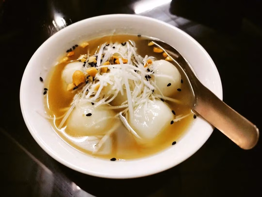 Nước đường nấu từ mật mía hoặc đường thốt nốt, thêm lá dứa và gừng thái sợi, đun liu riu để nước sánh và thơm. Khi bánh nổi lên, chỉ cần vớt ra, rắc thêm vừng, lạc, dừa nạo, món ăn đã sẵn sàng thưởng thức. Ảnh iVIVU