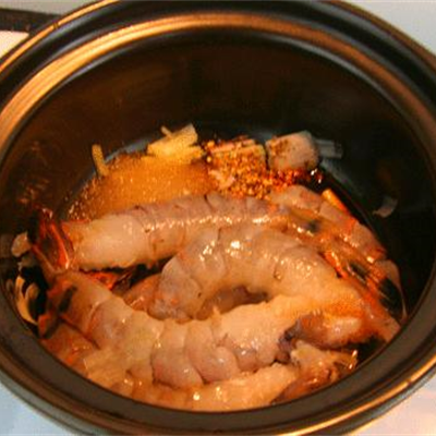 4. Tôm kho nồi đất. Nguyên liệu: Tôm, tỏi, hành tím, dầu ăn, gia vị: nước nắm, bột nêm, đường, tiêu, hành lá. Tôm làm sạch, hành tỏi bằm nhỏ. Phi thơm hành tỏi vào nồi đất. Cho tôm vào xào săn lại, thêm nước mắm, bột nêm, đường, tiêu và nước vừa mặt tôm. Ảnh: Cooky.vn.