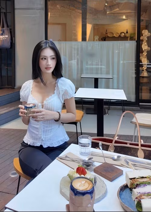 Tại quán cà phê, Ý Nhi chọn áo ôm tay phồng màu trắng phối quần tối màu. Bộ trang phục tôn vóc dáng mảnh mai cùng vòng eo gọn gàng của nàng hậu.