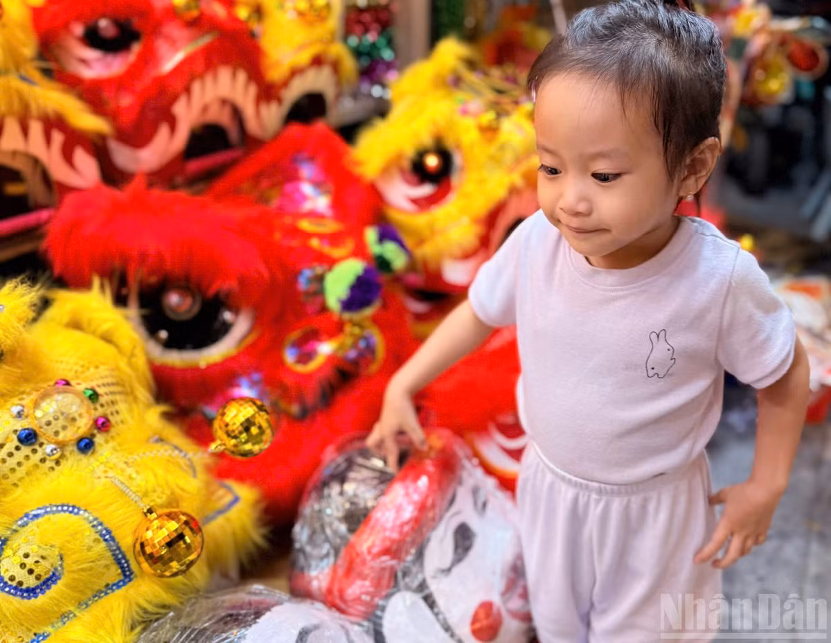Những em nhỏ được bố mẹ cho dạo chơi phố Hàng Mã, bị thu hút bởi đầu lân, mặt nạ giấy bồi.