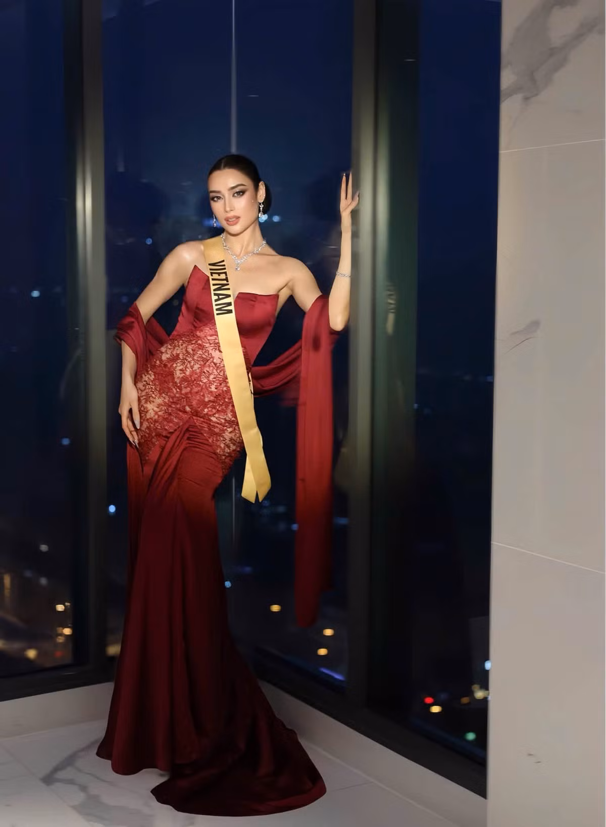 Với váy dạ hội đỏ rượu vang, Emoura Phạm chuyển sang phong cách sang trọng. Thiết kế ôm sát cơ thể, phần choàng dài ở hai tay giúp tôn chiều cao và vóc dáng thanh mảnh của cô.