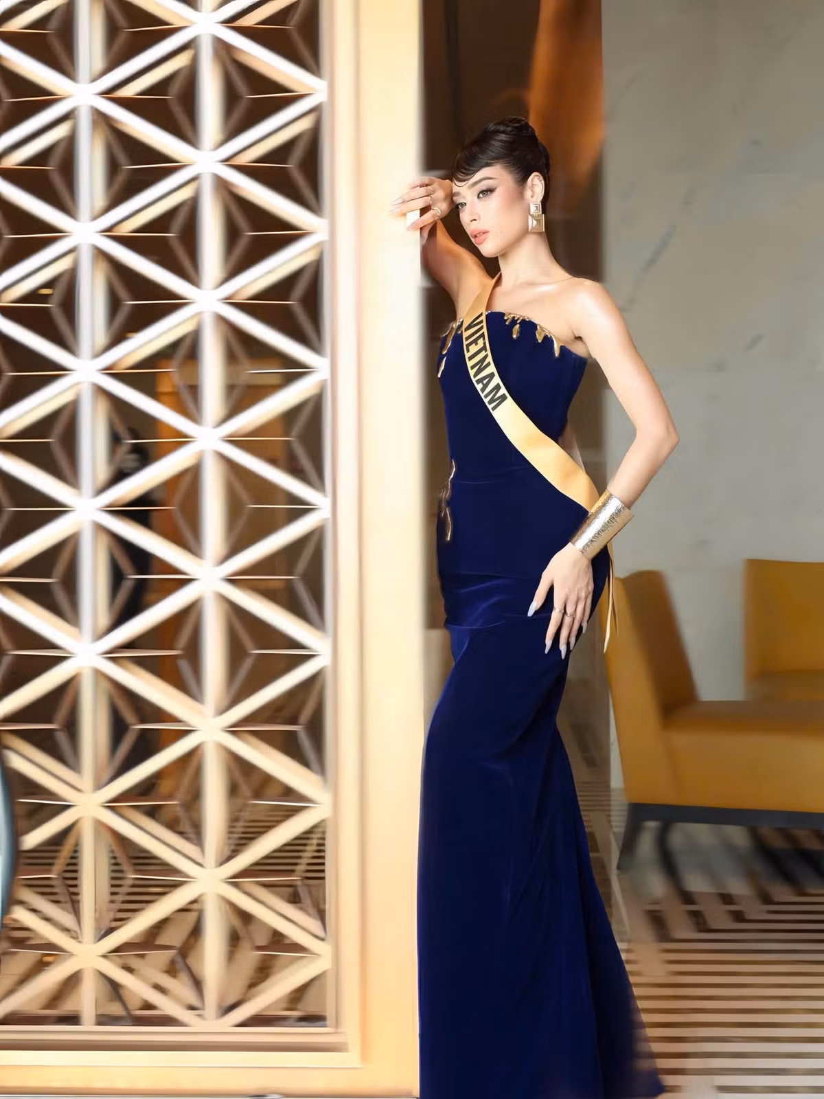 Đại diện Việt Nam tiếp tục lựa chọn phom váy ôm dáng nhưng thay đổi với sắc xanh đậm. Chi tiết ánh kim ở phần ngực cùng vòng tay bản lớn tạo điểm nhấn, trong khi tóc búi cao giúp tổng thể gọn gàng.