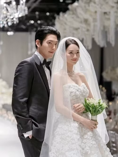 Trong hôn lễ, Shin Min Ah khoác trên mình chiếc váy trắng cúp ngực, họa tiết hoa. Kim Woo Bin diện bộ vest đen lịch lãm. Ảnh: VTV.