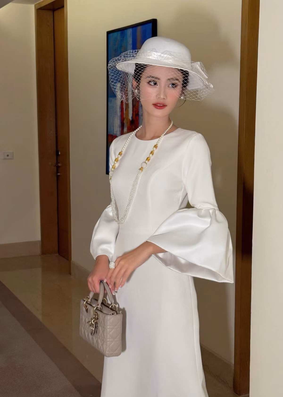 Ngày thứ 16 tham gia cuộc thi Miss World 2025, Hoa hậu Ý Nhi diện set đồ trắng thanh lịch kết hợp với phụ kiện mũ đính lưới, vòng cổ ngọc trai. Ảnh: FB Ý Nhi.
