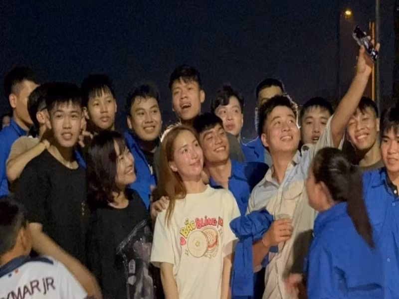 Nữ ca sĩ chụp ảnh kỷ niệm cùng đoàn viên thanh niên tham gia đắp đê. Ảnh: Tiền Phong.