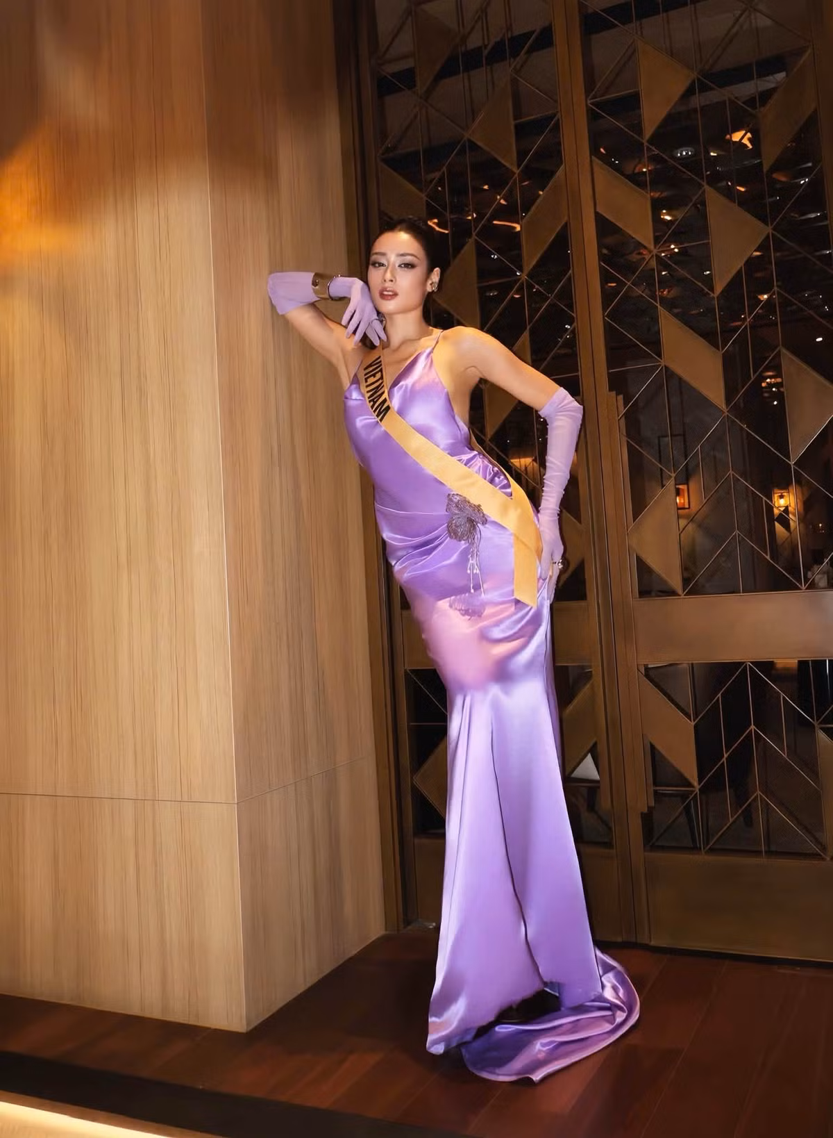 Chuyển sang chất liệu satin màu tím, Emoura Phạm chọn váy hai dây ôm sát, kết hợp găng tay đồng màu. Trang phục tạo sự khác biệt so với những bộ váy có cấu trúc cầu kỳ cô diện trước đó.