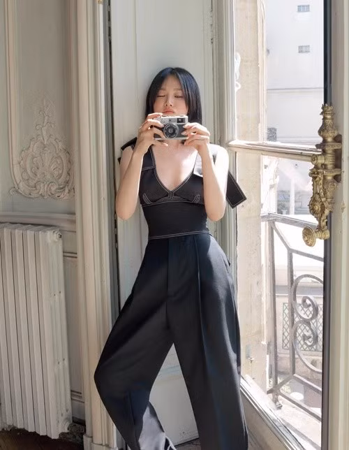 Song Hye Kyo xuất hiện với trang phục liền thân màu đen cổ sâu, kết hợp tạo dáng chụp ảnh bên cửa sổ ngập nắng. Thiết kế giúp tôn vóc dáng thanh mảnh của nữ diễn viên.
