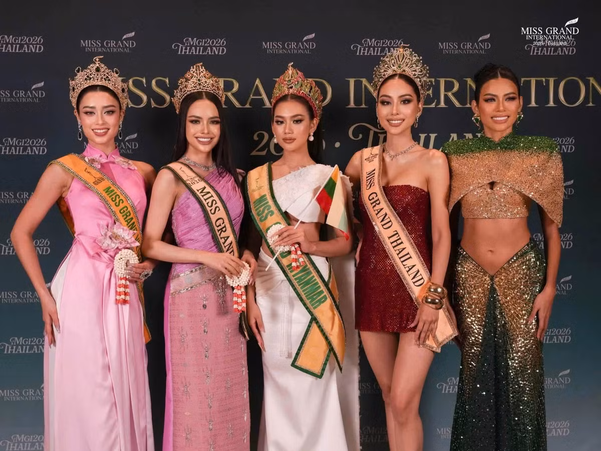 Emoura Phạm xuất hiện bên các thí sinh quốc tế trong một hoạt động của cuộc thi. Người đẹp Việt diện trang phục tông hồng, kết hợp sash Miss Grand Vietnam 2026 và kiểu tóc búi gọn.