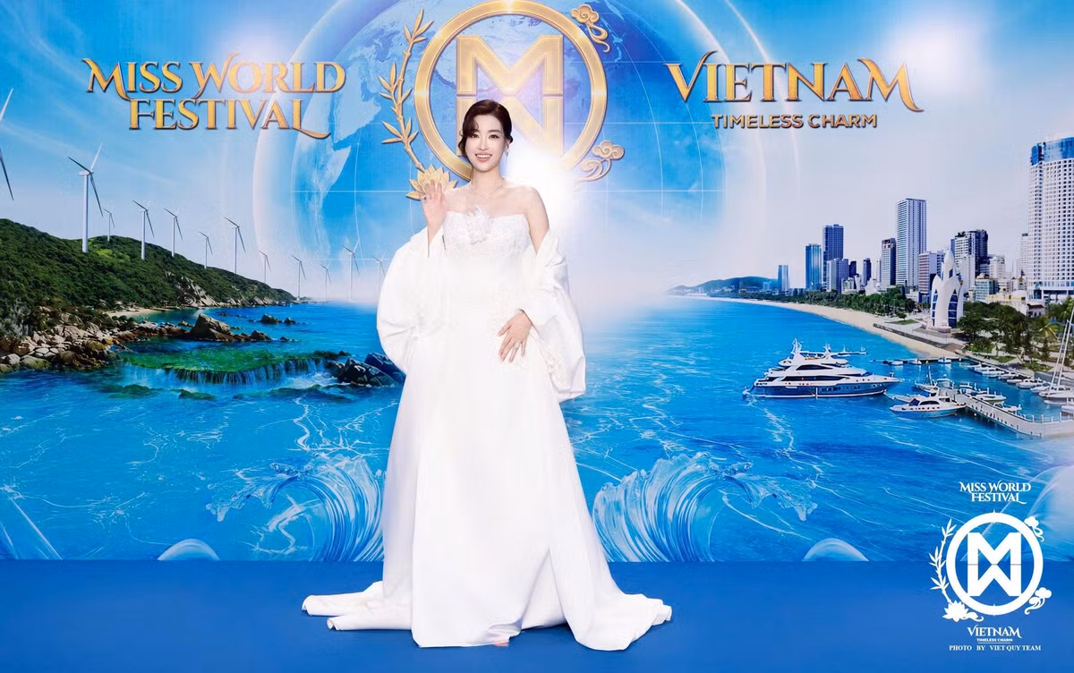 Hoa hậu Đỗ Mỹ Linh chọn váy trắng dáng dài trên thảm xanh chung kết Miss World 2026. Thiết kế quây, điểm chi tiết hoa ở thân trên, kết hợp phần choàng tạo độ phồng ở hai tay. Cô búi tóc gọn và sử dụng trang sức thanh mảnh.