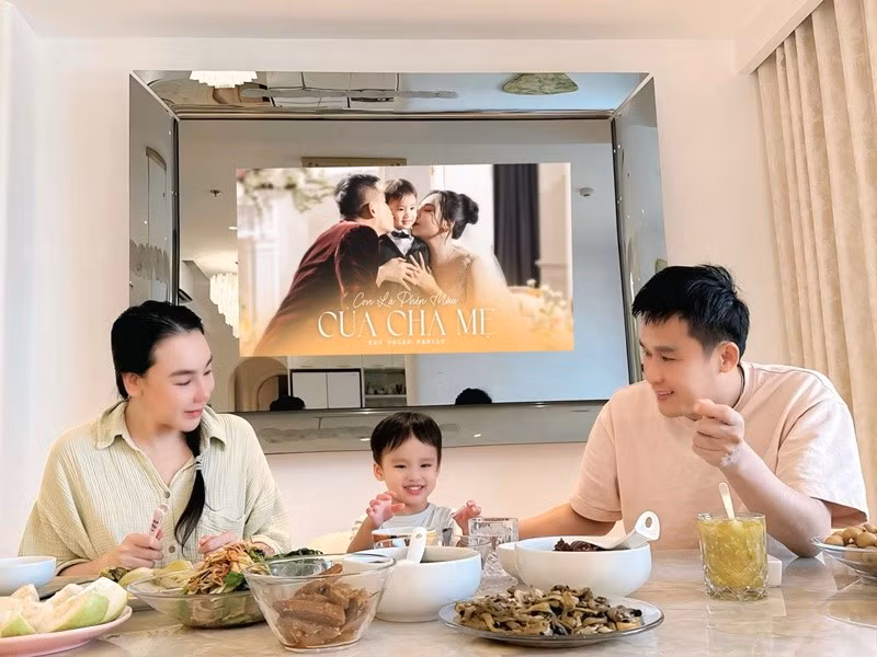 Khoảnh khắc gia đình quây quần bên bàn ăn thu hút sự chú ý. Hồ Quỳnh Hương xuất hiện với gương mặt mộc hoặc trang điểm nhẹ, diện áo sơ mi giản dị và ân cần chăm sóc con. Ảnh: FB Táo Vegan Family.