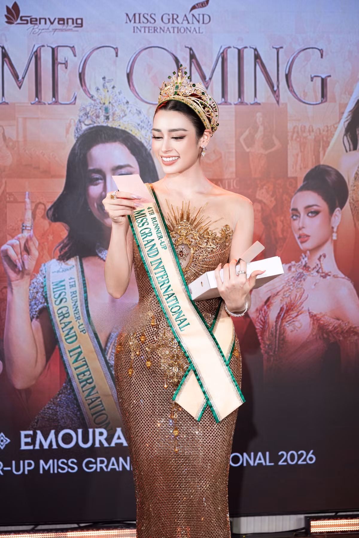 Tại buổi homecoming, Emoura Phạm chăm chú đọc thiệp và đón nhận những món quà từ khán giả. Người đẹp bày tỏ sự biết ơn trước tình cảm mà mọi người dành cho cô sau hành trình thi quốc tế.