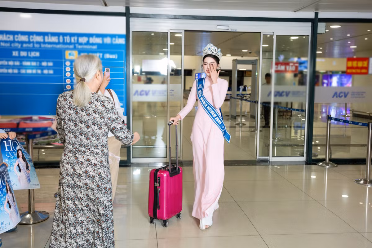 Xuất hiện tại sân bay, người đẹp diện áo dài truyền thống, đeo sash và đội vương miện. Hình ảnh ấy không chỉ gợi nhắc khoảnh khắc đăng quang mà còn cho thấy sự chỉn chu, tự hào khi nàng hậu trở về trong vai trò mới. Xen lẫn nụ cười rạng rỡ là cảm giác hồi hộp rất đời thường của một cô gái sau thời gian dài xa nhà.