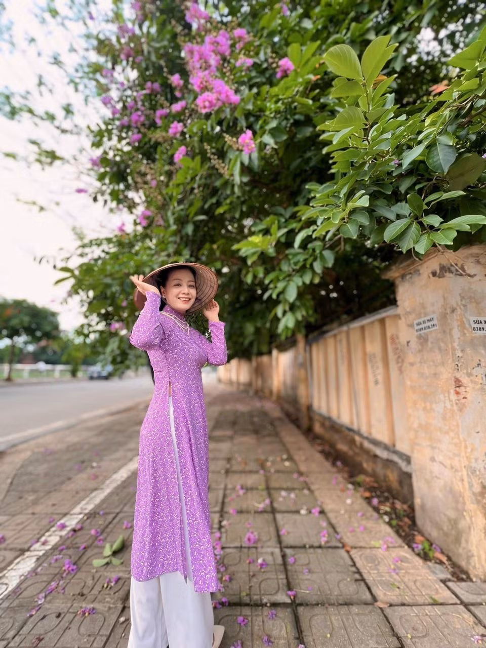 Diễn viên Chiều Xuân diện áo dài tím, chụp ảnh bên hoa bằng lăng.