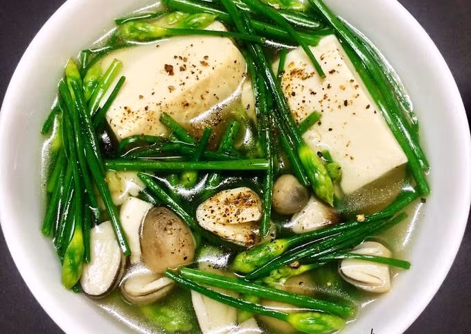 Canh hẹ nấu đậu non: 3 miếng đậu hũ non, 200 gam lá hẹ. Đậu hũ non đem rửa nhẹ nhàng với nước, tránh làm đậu vỡ nát, sau đó cắt thành những miếng vuông nhỏ vừa ăn. Lá hẹ đem rửa sạch, cắt khúc nhỏ, để ráo nước. Cho nồi lên bếp, phi hành với dầu ăn cho thơm rồi đổ nước vào, nấu sôi. Khi nước sôi, cho đậu hũ non vào trong nồi, nêm nếm gia vị cho vừa ăn. Đợi nước sôi thêm khoảng 5 phút nữa thì cho rau hẹ vào, đợi nước sôi lại thì tắt bếp. Múc canh ra tô. Ăn món trên với cơm và ăn khi nóng. Ảnh minh họa