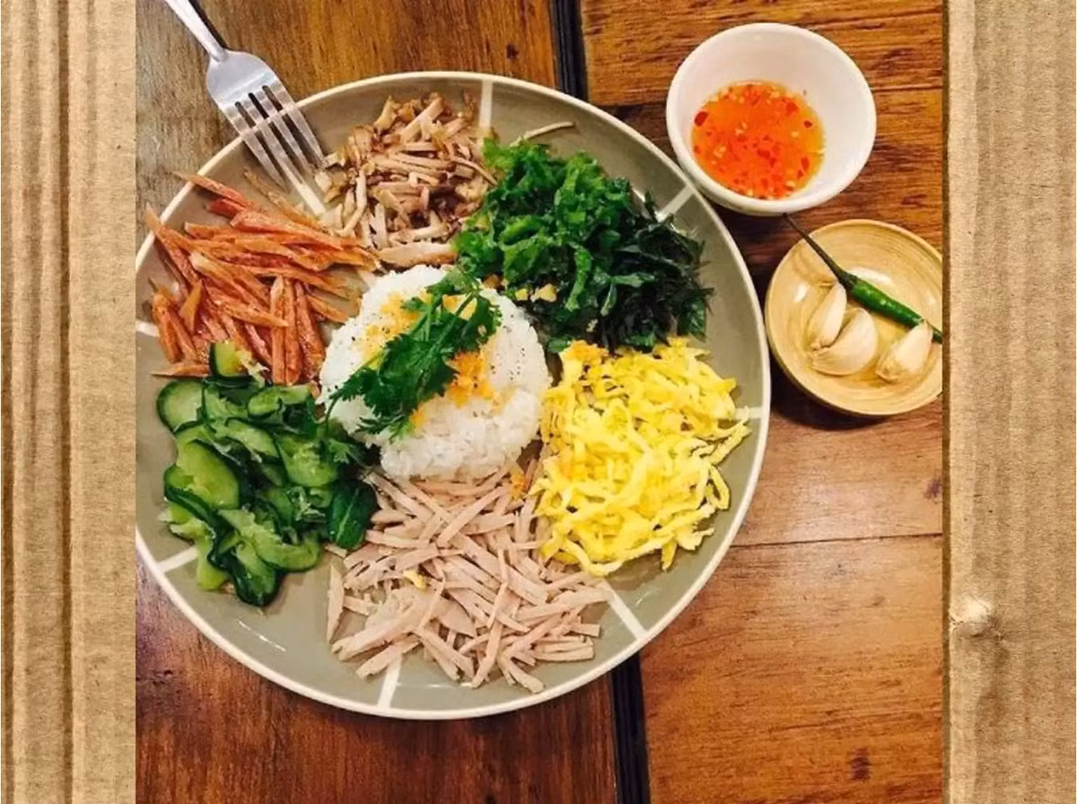Cơm âm phủ Huế là một trong những món ăn đặc sản mang đậm nét văn hóa Huế. Món ăn được chế biến từ nhiều nguyên liệu, cơm trắng thường đặt ở giữa, xung quanh là rau xanh, cải chua, thịt ba rọi, nem chua, chả Huế,... và được trang trí bằng một ít hành, ngò. Ảnh: Traveloka