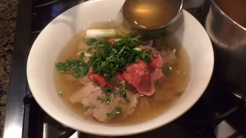 Chan nước dùng nóng hổi vào tô, xếp bánh phở, thịt bò, rau sống lên trên. Thêm một chút tiêu xay và hành lá thái nhỏ. Ảnh: Bách hoá Xanh