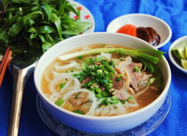 Bí quyết để có một bát phở bò Nam Định ngon, chuẩn vị là chọn nguyên liệu tươi ngon, hầm xương kỹ. Khi thưởng thức phở Nam Định, bạn nên chan thêm một chút nước mắm ngon để tăng thêm hương vị. Ảnh: Mytour