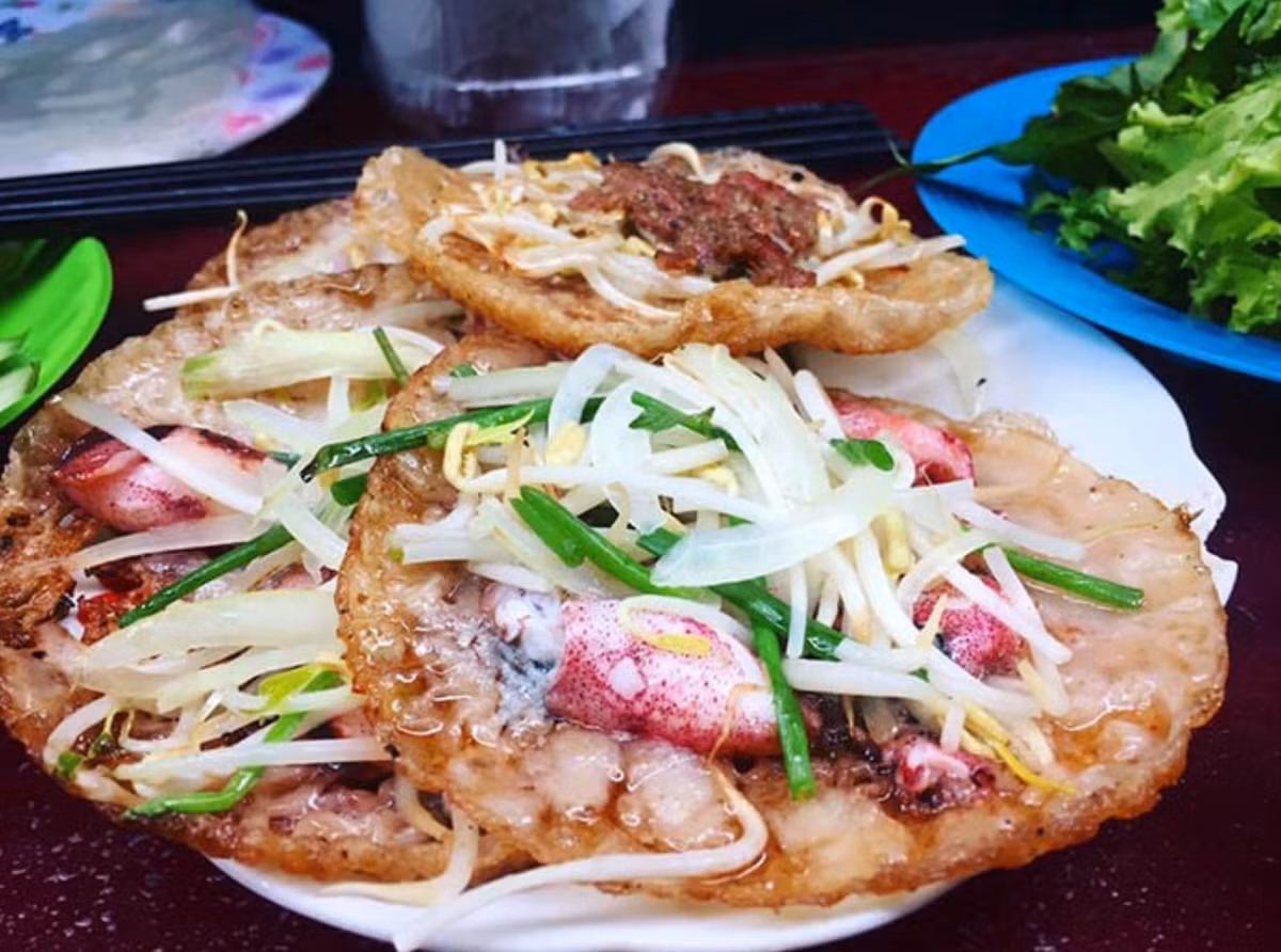 Bánh xèo mực là ón ăn dân dã với lớp vỏ vàng giòn rụm, nhân mực tươi ngon cùng giá đỗ xanh, ăn kèm rau sống và nước chấm chua ngọt.