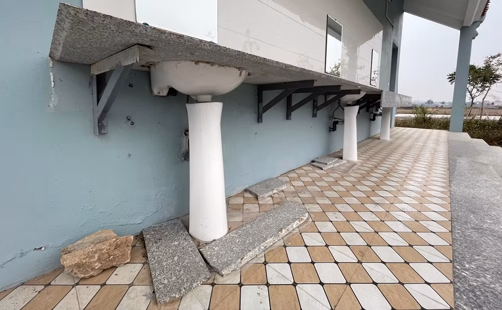 Một phần đá chậu rửa mặt bị rơi vỡ nát. Sơn tường bong tróc.