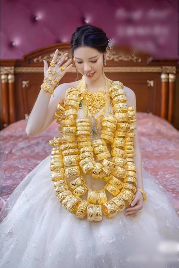 Cô dâu đeo lên cổ toàn là vàng, từ ngón tay, cổ tay đến cổ. Thậm chí, người nhà còn phải xâu các lắc vàng bản lớn thành 2 đến 3 chuỗi vòng, đeo lên cổ cô dâu để thuận tiện đi lại.