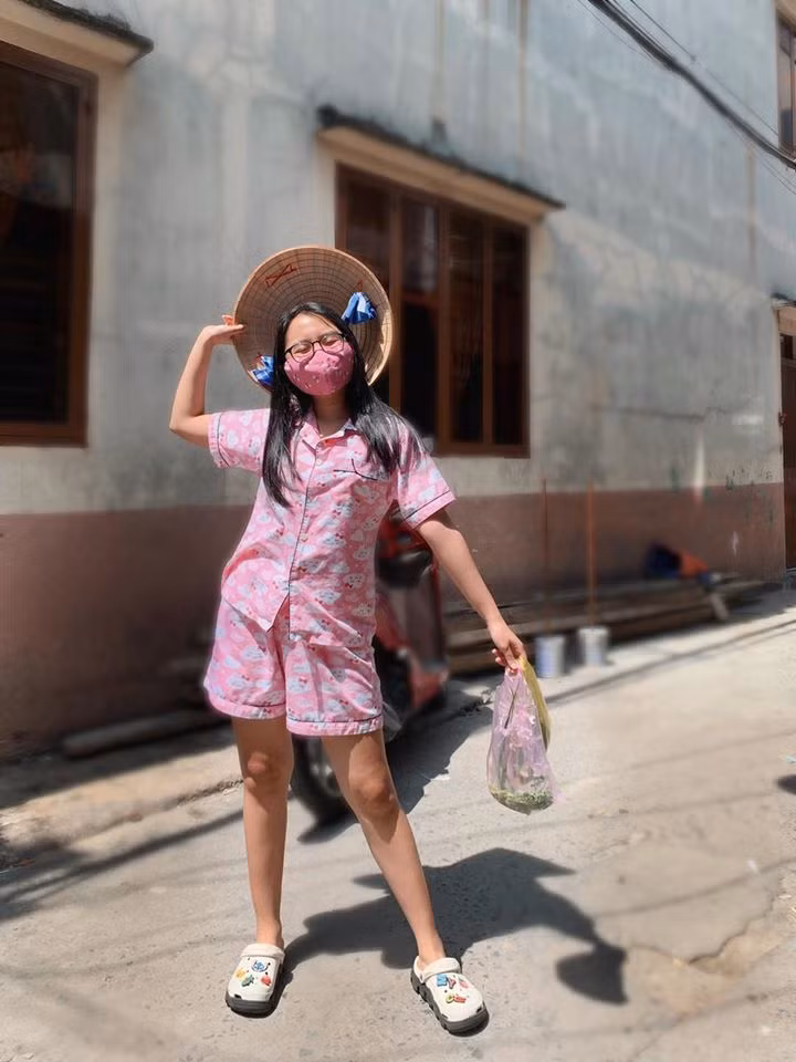 Phương Mỹ Chi tạo dáng đáng yêu, đeo khẩu trang cẩn thận đi chợ dù chợ rất gần nhà. Ca sĩ 17 tuổi kêu gọi sử dụng khẩu trang vải vì tiện dụng, an toàn và tiết kiệm.