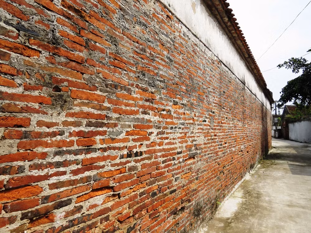 Tường nhà được xây bằng gạch đất nung bản mỏng, kích thước mỗi viên gạch dài tới 40 cm, rộng ngang 30 cm. Ảnh: Vnexpress.