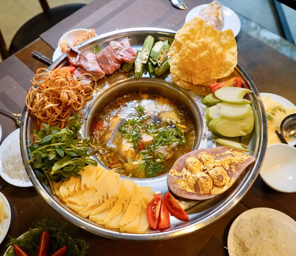Mỗi nồi lẩu cá dát vàng gồm một khúc cá được dát vàng lá 24k, những miếng cá cắt nhỏ có xương và đồ nhúng kèm. Ảnh: Internet