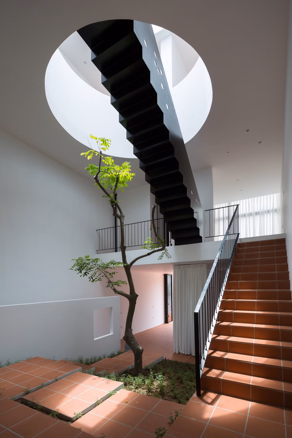  Kiến trúc nhà ở hiện đại đan xen âm hưởng dân gian thể hiện ngay từ không gian tầng 1 qua trần cao với hình khối đơn giản kết hợp cùng gạch nung đất đỏ.