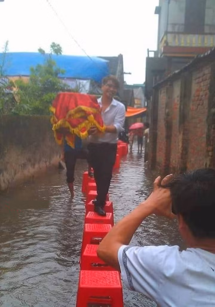 Khi nước dâng cao, mọi người đã phải xếp ghế thành hàng để đoàn rước dâu có thể di chuyển tránh bị ướt trang phục.