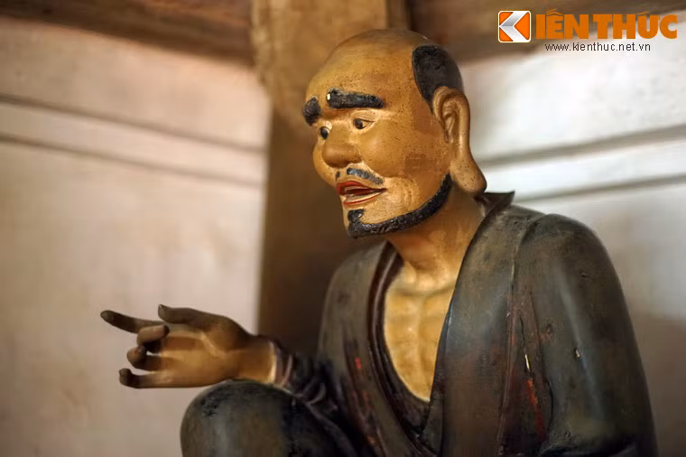 Tượng ông tay trái cầm một cuộn sách, tay phải cầm một thẻ tre (đã bị mất), được tạo dáng ngồi nhấp nhổm rất sinh động.