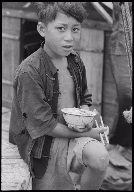 Bữa trưa trên mạn thuyền của một cậu bé vạn chài Hong Kong. Ảnh: Werner Bischof/ Magnum Photos.