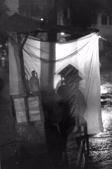 Một quầy hàng vỉa hè trong đêm mưa Sài Gòn. Ảnh: Ferdinando Scianna/ Magnumphotos.com.
