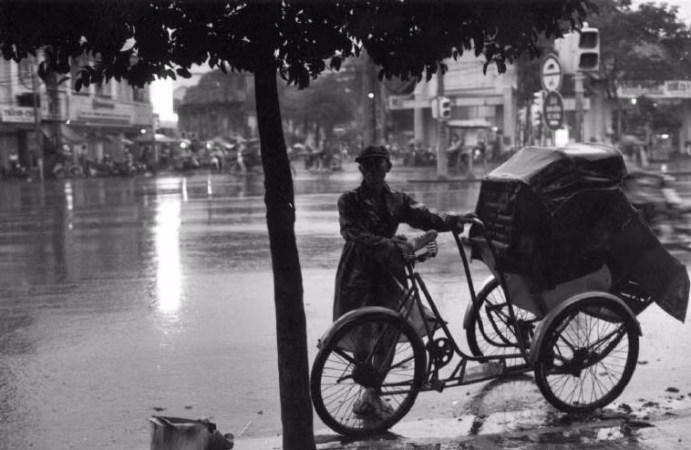 Người lái xích lô trú mưa dưới tán cây. Ảnh: Ferdinando Scianna/ Magnumphotos.com.