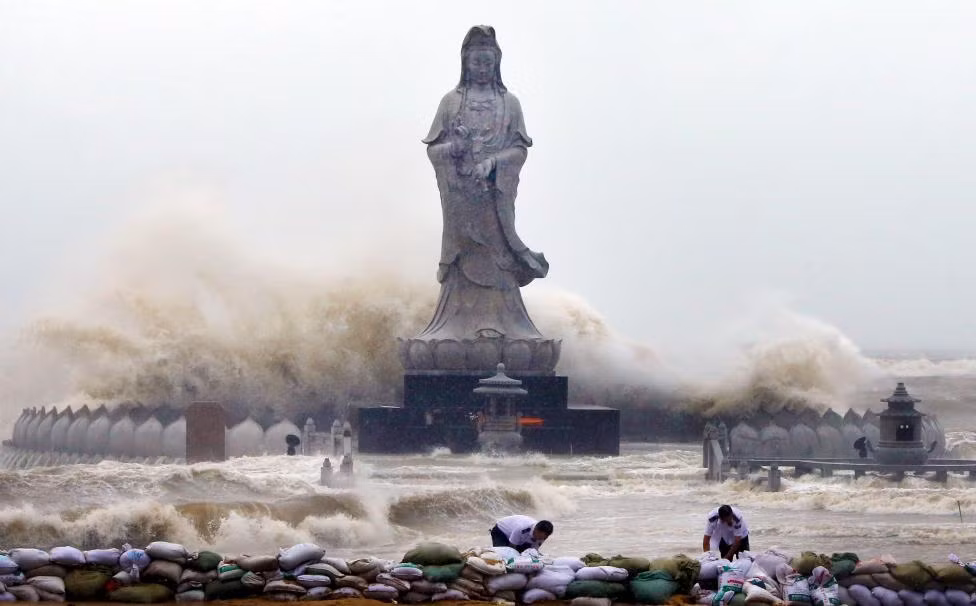Người dân gấp rút lấy túi cát làm bờ kè ngăn nước lũ bao quanh tượng Quan Thế Âm Bồ Tát nằm bên bờ biển ở Tuyền Châu, tỉnh Phúc Kiến.