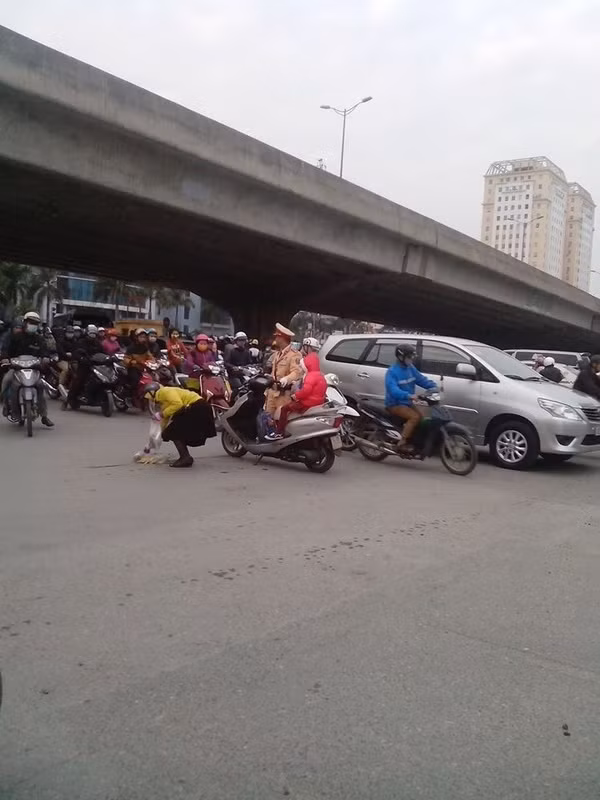 Còn đây là bức ảnh chụp vào buổi chiều 16/12 trên đoạn ngã từ Tôn Thất Thuyết - Phạm Hùng, Hà Nội với câu chuyện kể về hành động đẹp của một anh cảnh sát giao thông. Giữa lòng đường đông đúc, bà mẹ chở một em nhỏ trên xe máy không may đánh rơi túi đồ, một chiến sĩ cảnh sát giao thông đang làm nhiệm vụ điều phối, phân luồng gần đó nhìn thấy sự việc nên đã đi tới trợ giúp cho bà mẹ. Anh cảnh sát giao thông vừa quan sát xung quanh, cố gắng vừa làm nhiệm vụ của mình, vừa giúp giữ xe, giữ em nhỏ khỏi ngã để bà mẹ nhặt đồ đánh rơi. Câu nói của anh cảnh sát với em bé: "Cháu ngồi im nhé, kẻo ngã đấy!" mà dân mạng truyền tai nhau đã khiến nhiều người theo dõi câu chuyện này cảm thấy ấm lòng. Ảnh: Nguyễn Phương Mai.