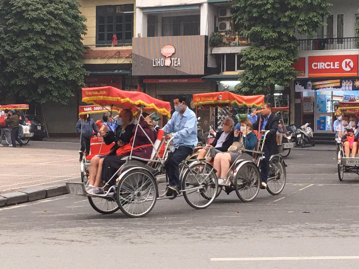 Một số hành khách chấp hành việc đeo khẩu trang khi được các bác tài xế xích lô yêu cầu khi đi dạo phố cổ.