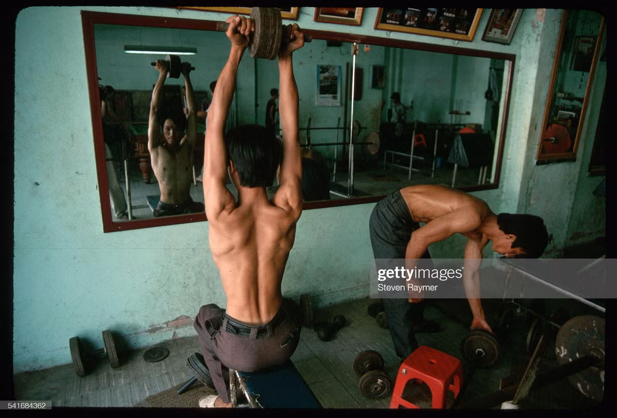 Các nam giới đẩy tạ trong một câu lạc bộ thể hình, 1994.