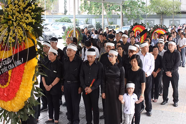 Chị Hồng Anh (áo dài, đeo kính đen) - cô con gái duy nhất của nghệ sĩ Duy Thanh cố nén đau thương để cùng gia đình lo tang lễ cho cha.