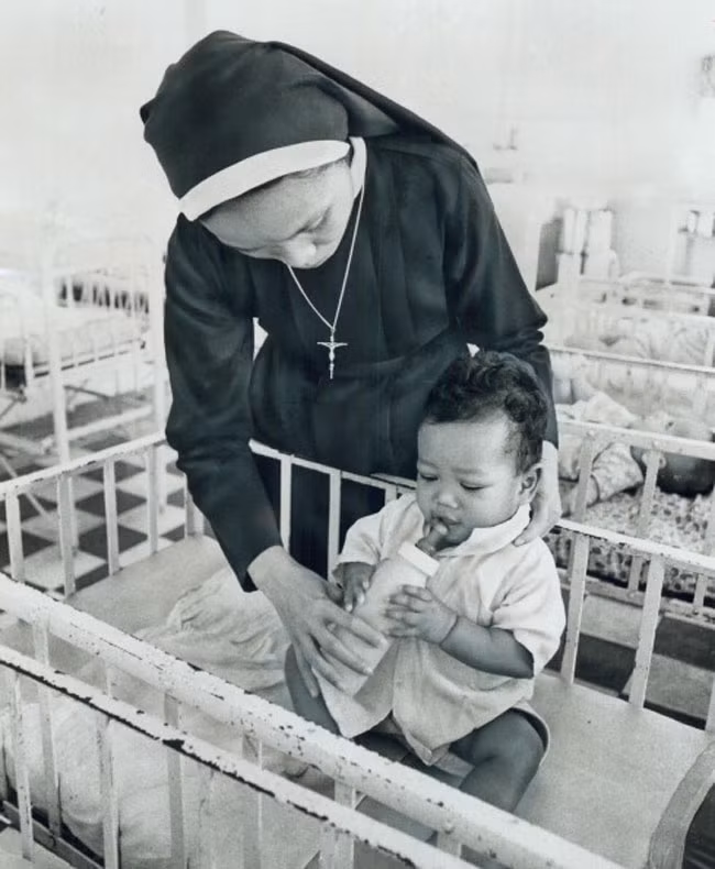 Sơ Theresa Khen giữ bình sữa cho một em bé mồ côi - là con lai của người mẹ Việt và bố là lính Mỹ da đen - ở cô nhi viện Gò Vấp, ngoại ô Sài Gòn.