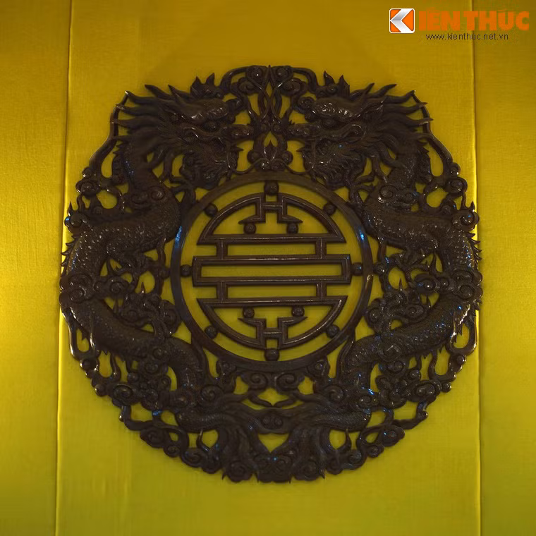 Trên đầu giường treo bức phù điêu bằng gỗ có hình hai con rồng ôm chữ Phúc.
