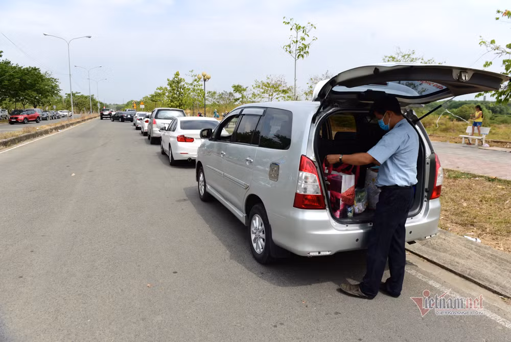 "Trong khu cách ly, đội ngũ y tế, lực lượng hậu cận, bảo vệ rất chu đáo. Đồ ăn, nước uống, khẩu trang, nước rửa tay có đầy đủ, đảm bảo dinh dưỡng nên mong người thân đừng lo. Khi đón kiều bào về nước, nhà nước ta đã tính hết các phương án, tạo điều kiện tốt nhất cho người cách ly. Mong các ông bố bà mẹ chỉ nên mang đồ dùng thật sự cần thiết", chiến sỹ công an nhắn nhủ. (Xe ô tô chở đồ tiếp tế xếp hàng dài ngoài đường)