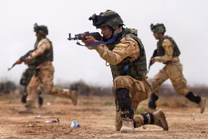 Một lính Iraq yểm trợ cho các binh sĩ khác vượt qua đường trong một bài huấn luyện tại trại Taji.