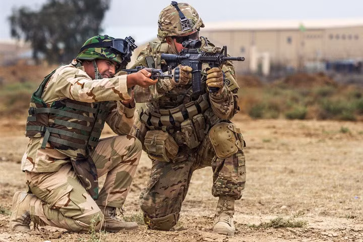 Trung sĩ lục quân Mỹ (bên phải) thị phạm tư thế quỳ bắn đúng cho một lính Iraq học theo.