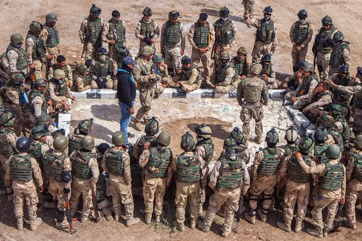 Binh sĩ Iraq quây xung quanh để xem quân nhân Mỹ dùng sa bàn hướng dẫn cách xử lý trước tình huống bị phục kích.
