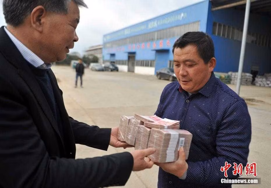 Một đại gia Trung Quốc khác cũng gây sốt khi phát những cục tiền thưởng Tết dày cộp cho 90 nông dân làm việc tại doanh nghiệp của mình. Ảnh: China News.