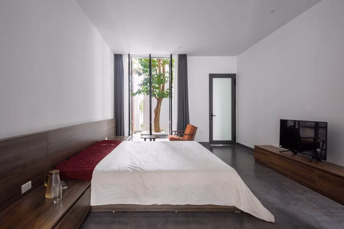 Phòng ngủ chính ở tầng 1 cũng được kết nối ra sân vườn rất thoáng đãng nhờ hệ cửa kính xoay cỡ lớn.