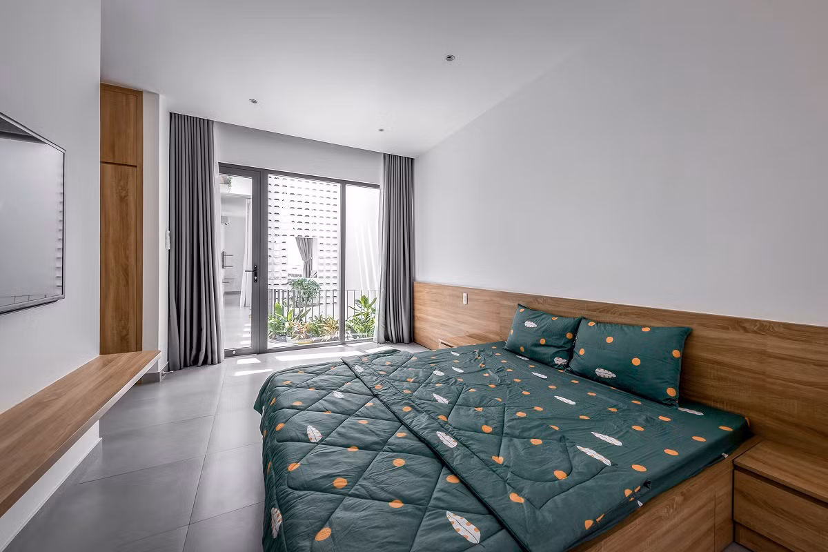 Vách phòng ngủ với mảng kính lớn nhìn ra giếng trời và mảng xanh giúp cho chúng ta thư giãn hơn khi ở trong phòng. Nguồn ảnh: Bùi Minh Quốc